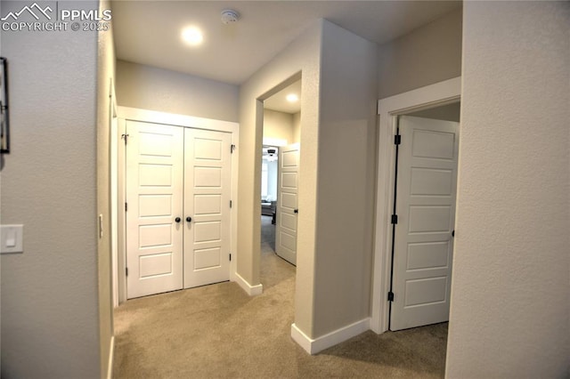 corridor featuring baseboards and carpet flooring