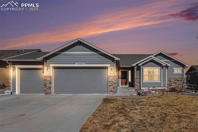 view of front of property featuring stone siding, driveway, roof with shingles, and an attached garage