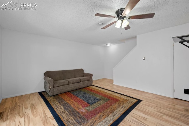 living room featuring a textured ceiling, wood finished floors, and baseboards