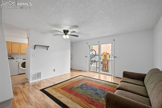 living area featuring light wood finished floors, visible vents, a ceiling fan, independent washer and dryer, and a textured ceiling