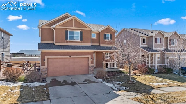 view of front of home with a garage, fence, driveway, stone siding, and stucco siding