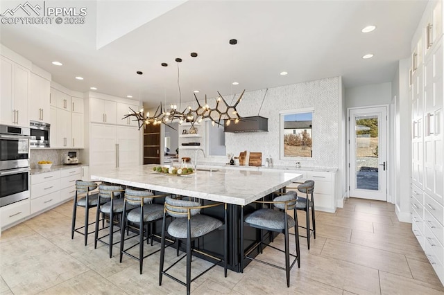 kitchen with white cabinets, a spacious island, appliances with stainless steel finishes, a breakfast bar area, and hanging light fixtures