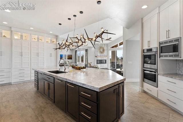 kitchen featuring appliances with stainless steel finishes, an island with sink, a sink, and white cabinetry