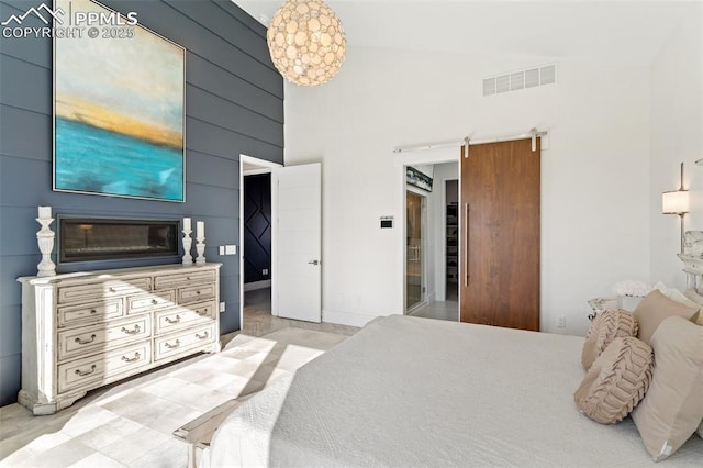 bedroom featuring a barn door, a towering ceiling, and visible vents