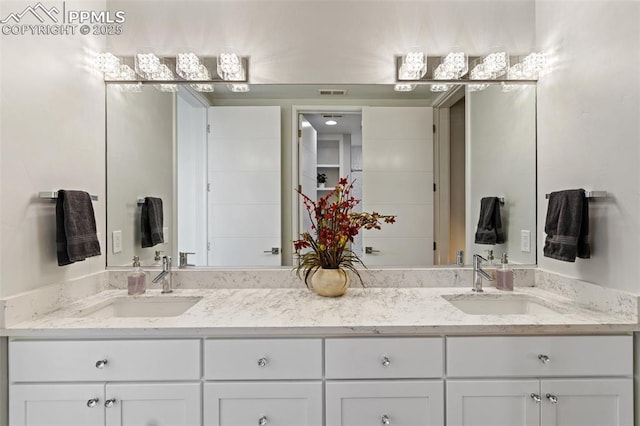 bathroom featuring visible vents, a sink, and double vanity