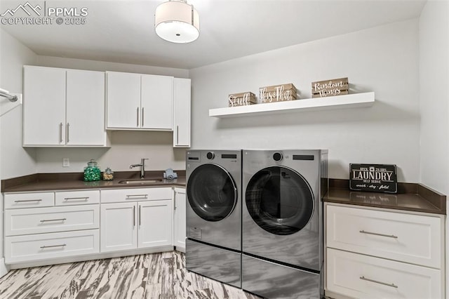 washroom with washing machine and dryer, cabinet space, and a sink