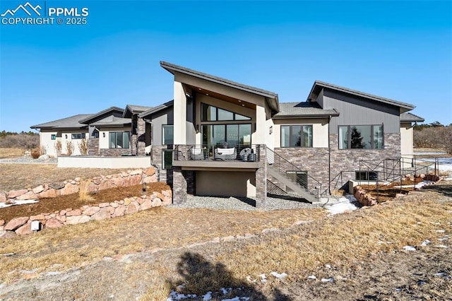 rear view of property with stone siding and stairs