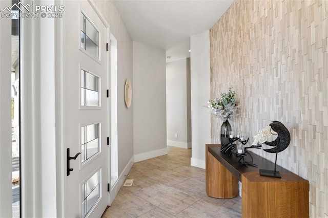 doorway with an accent wall, baseboards, and light tile patterned floors