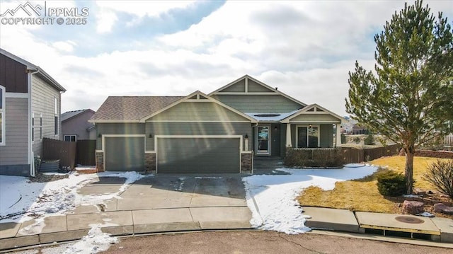 craftsman house featuring concrete driveway, stone siding, an attached garage, and fence