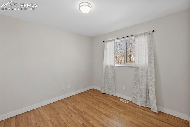 unfurnished room featuring baseboards, visible vents, and light wood-style floors