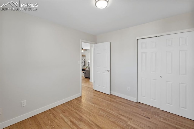 unfurnished bedroom featuring light wood-style floors, baseboards, and a closet