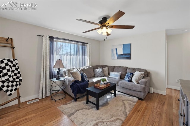 living area featuring baseboards, a ceiling fan, visible vents, and light wood-style floors