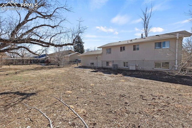 back of house featuring central AC and fence