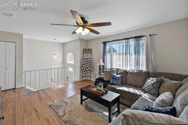 living area with wood finished floors, a ceiling fan, and baseboards