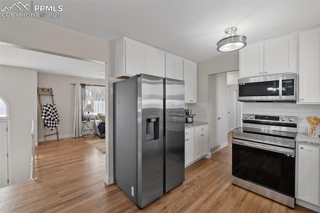 kitchen with light wood finished floors, visible vents, white cabinets, light stone countertops, and stainless steel appliances