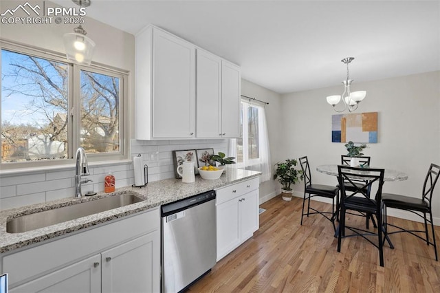 kitchen featuring white cabinets, dishwasher, decorative light fixtures, and a sink