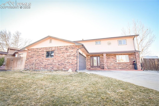 traditional-style home with a garage, concrete driveway, brick siding, and fence