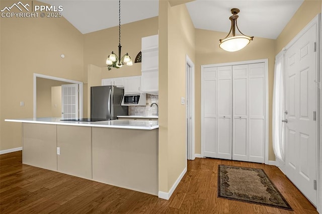 kitchen with dark wood-style flooring, tasteful backsplash, light countertops, hanging light fixtures, and appliances with stainless steel finishes