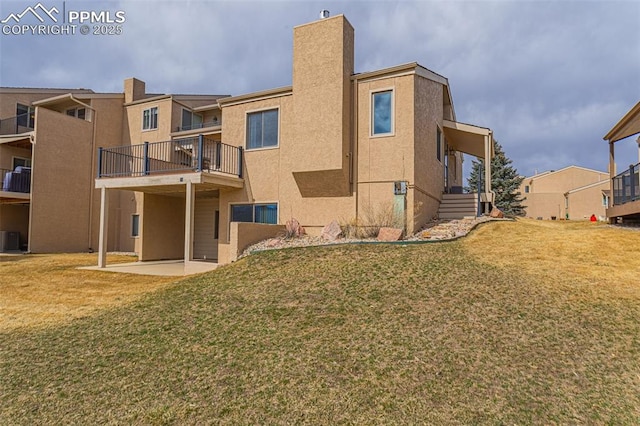 rear view of property with stucco siding, a patio area, and a yard