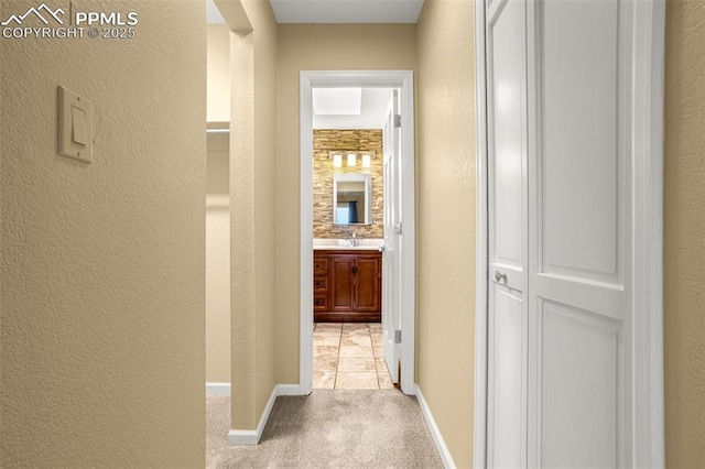 hall with carpet, a textured wall, and baseboards