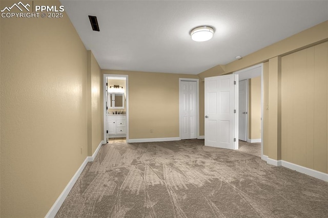 unfurnished bedroom with ensuite bathroom, carpet floors, and baseboards