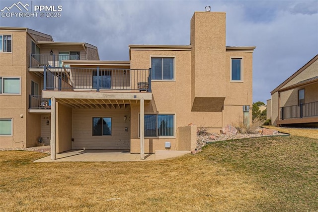 rear view of property with a yard, a patio, and stucco siding