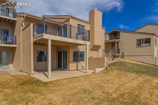 back of house featuring a yard, a patio, and stucco siding