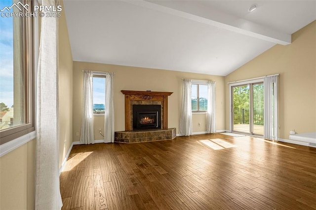 unfurnished living room with lofted ceiling with beams, wood finished floors, a high end fireplace, and baseboards