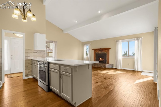 kitchen featuring a peninsula, light countertops, wood finished floors, and stainless steel range with electric cooktop