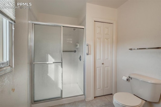 bathroom featuring toilet, a stall shower, tile patterned flooring, and a closet