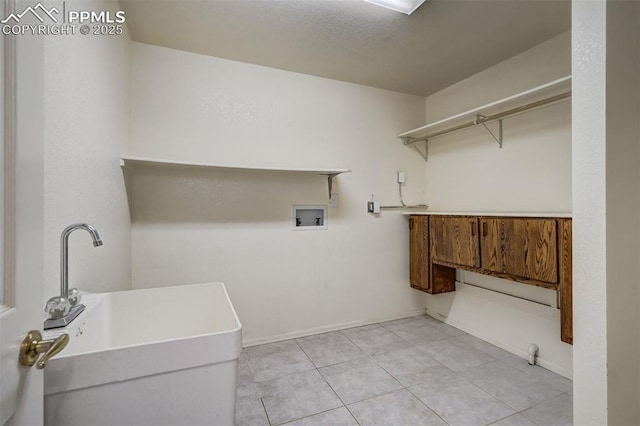 clothes washing area featuring light tile patterned floors, hookup for a washing machine, a sink, laundry area, and baseboards