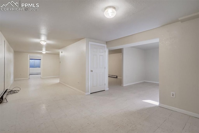 finished basement featuring light floors, a baseboard radiator, baseboards, and a textured ceiling