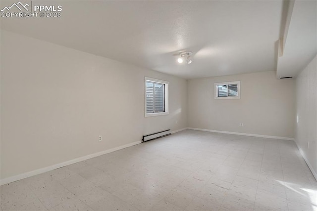 spare room with light floors, a baseboard radiator, and baseboards