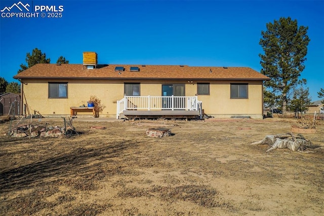 back of house featuring a deck and a storage shed