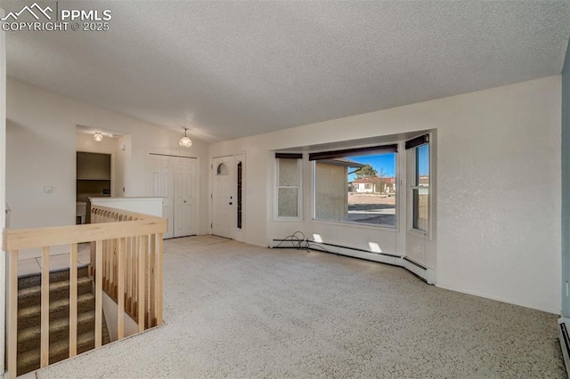 unfurnished room featuring lofted ceiling, a textured ceiling, baseboard heating, and a baseboard radiator