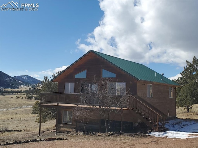 back of house with stairway, a mountain view, and metal roof