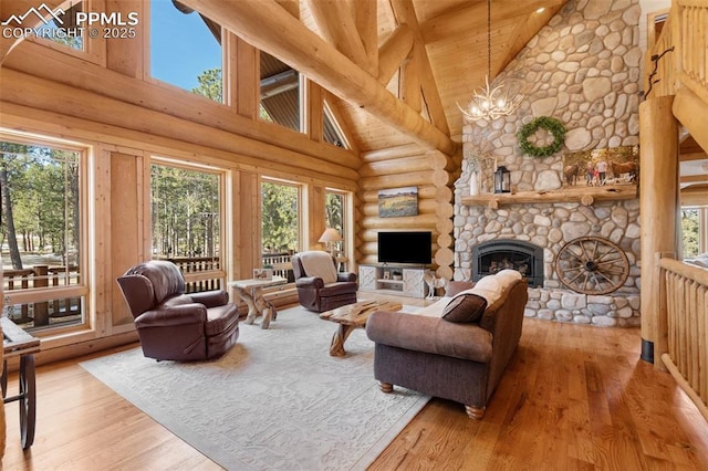 living room featuring light wood-style floors, plenty of natural light, a notable chandelier, and a stone fireplace