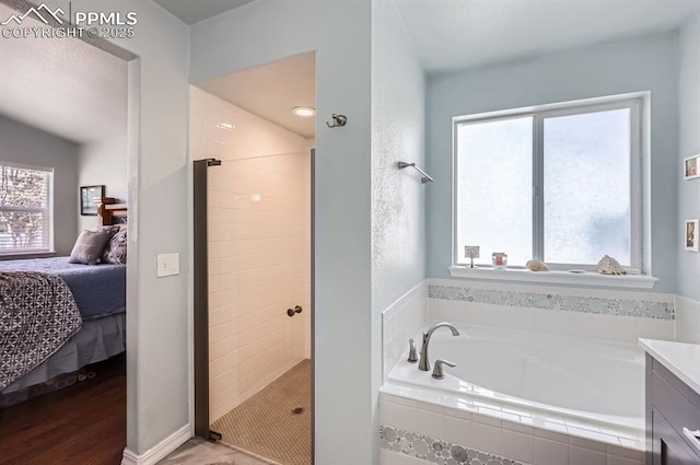 ensuite bathroom with a wealth of natural light, a stall shower, connected bathroom, and a bath