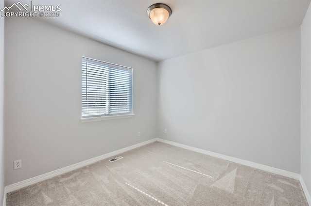 carpeted empty room featuring baseboards and visible vents