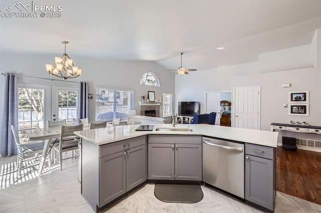 kitchen featuring open floor plan, light countertops, gray cabinetry, stainless steel dishwasher, and a sink