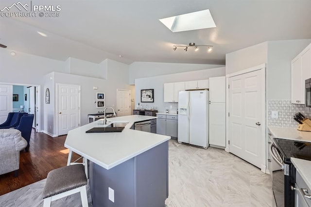 kitchen with vaulted ceiling with skylight, an island with sink, a breakfast bar area, appliances with stainless steel finishes, and a sink