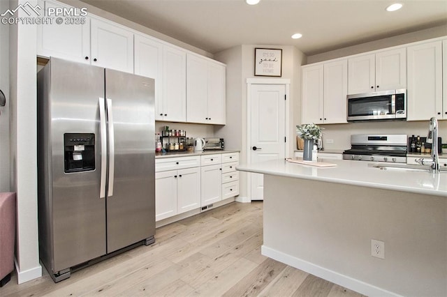 kitchen with stainless steel appliances, light wood finished floors, and white cabinets