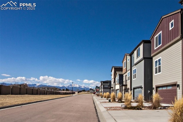 view of road with curbs, a mountain view, and a residential view