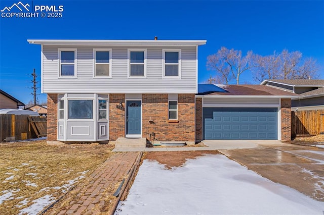 colonial inspired home with driveway, brick siding, an attached garage, and fence