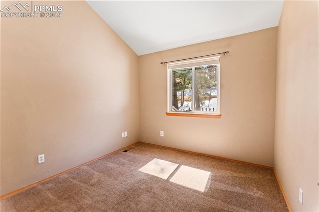 carpeted spare room featuring vaulted ceiling and baseboards