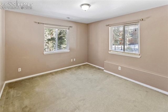 carpeted spare room with visible vents and baseboards