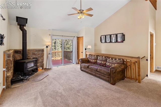 carpeted living area featuring visible vents, high vaulted ceiling, a wood stove, and a ceiling fan