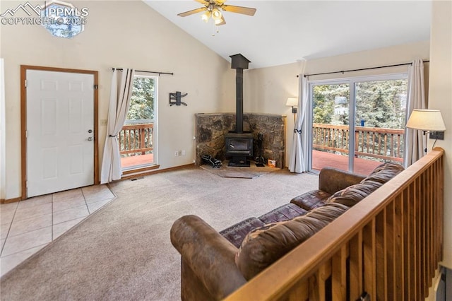 living room featuring tile patterned floors, carpet flooring, a wood stove, and a healthy amount of sunlight