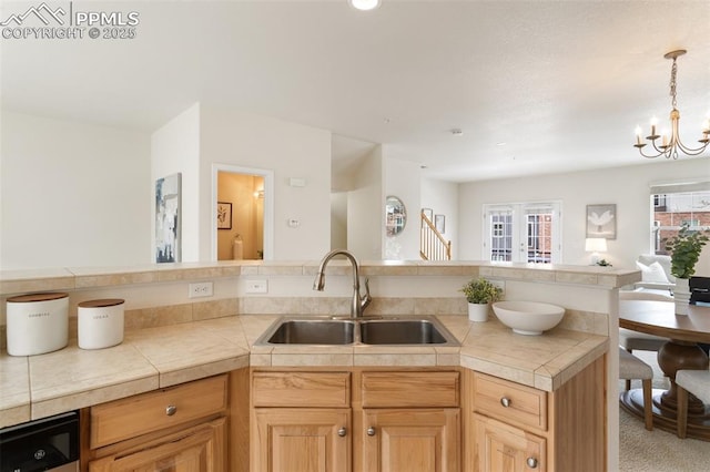 kitchen with dishwashing machine, a sink, open floor plan, decorative light fixtures, and an inviting chandelier