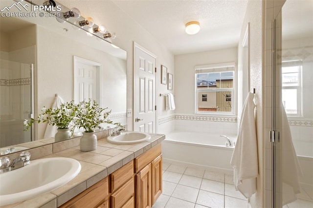 full bath featuring a bath, a stall shower, a sink, and tile patterned floors